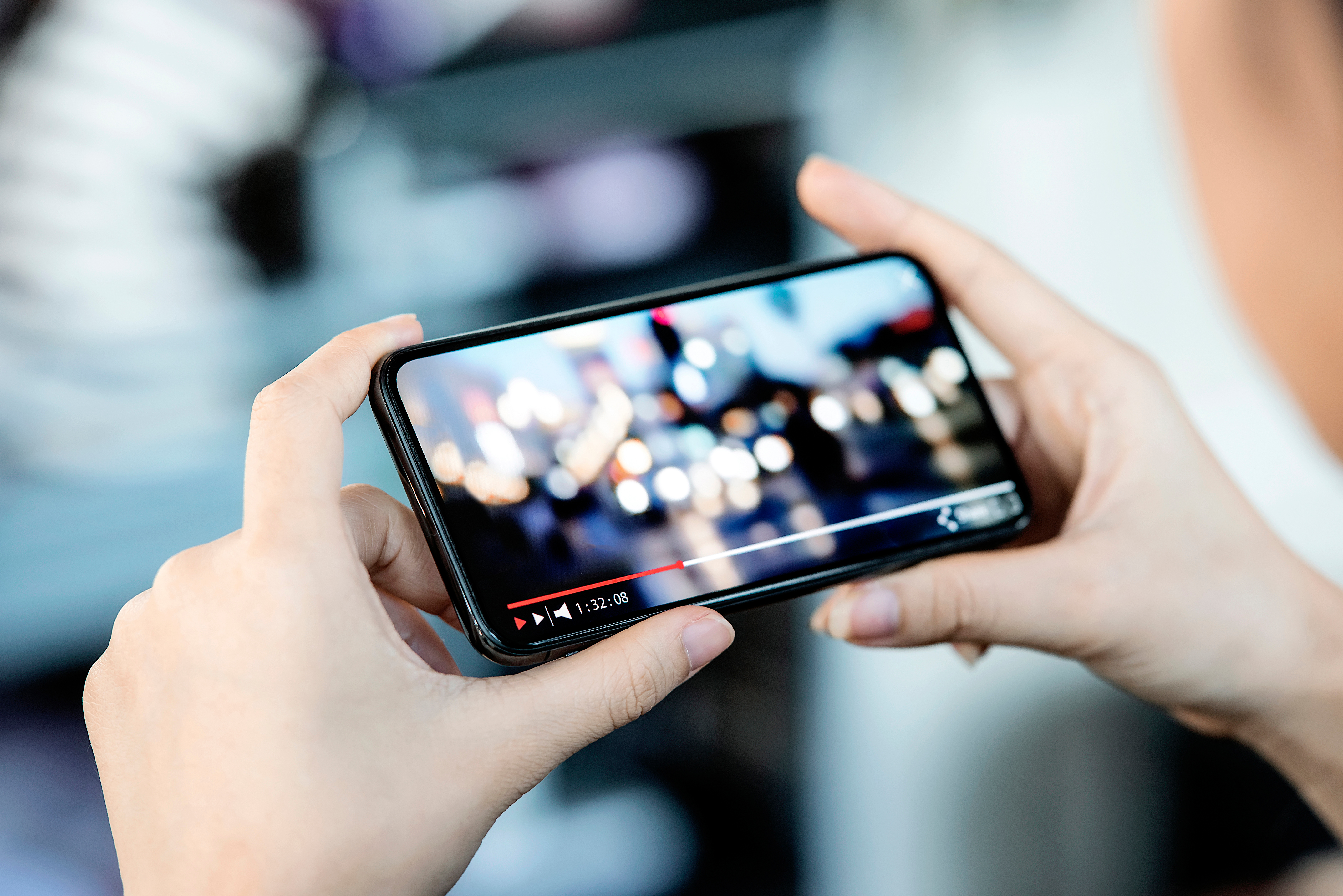 Cropped image of female hand holding smartphone and watching vid